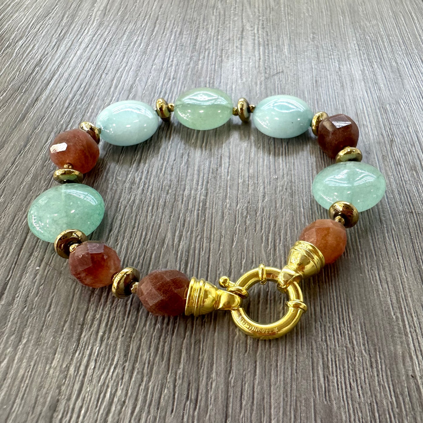 Dettaglio di bracciale artigianale con pietre naturali e chiusura in argento dorato