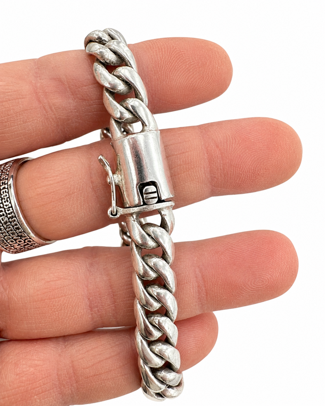 Dettaglio della chiusura di un bracciale Cuban Link in Argento 925 indossato da uomo, con maglia spessa e finitura vintage lucida.