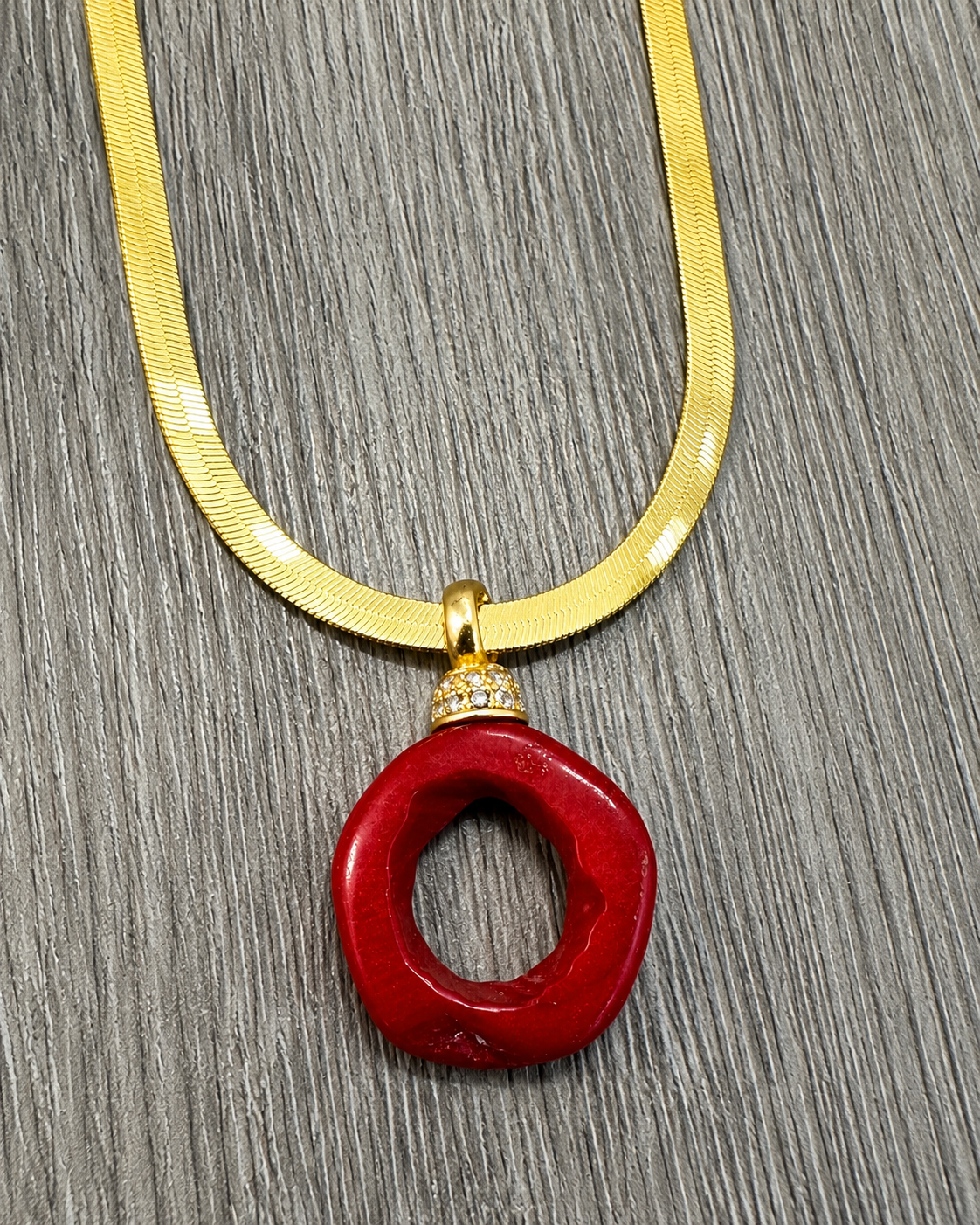 Dettaglio del pendente in corallo bambù rosso con coppetta impreziosita da zirconi su collana Snake in argento 925 dorato.