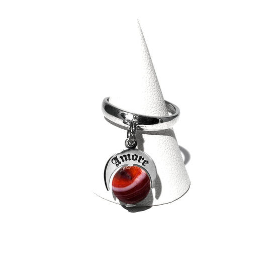 Caratteristiche: L'anello è composto da una base in Argento 925 e un Charm Naja. Quest'ultimo è inciso e smaltato, con scritte in carattere gotico e una Pietra Dura. Il Charm è attaccato alla base dell'anello con un piccolo moschettone che permette l'eventuale riposizionamento del charm stesso su un bracciale , una collana o un qualsiasi altro supporto