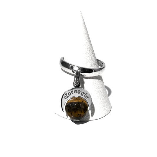 Caratteristiche: L'anello è composto da una base in Argento 925 e un Charm Naja. Quest'ultimo è inciso e smaltato, con scritte in carattere gotico e una Pietra Dura. Il Charm è attaccato alla base dell'anello con un piccolo moschettone che permette l'eventuale riposizionamento del charm stesso su un bracciale , una collana o un qualsiasi altro supporto