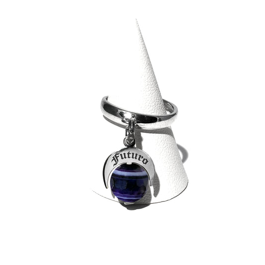 Caratteristiche: L'anello è composto da una base in Argento 925 e un Charm Naja. Quest'ultimo è inciso e smaltato, con scritte in carattere gotico e una Pietra Dura. Il Charm è attaccato alla base dell'anello con un piccolo moschettone che permette l'eventuale riposizionamento del charm stesso su un bracciale , una collana o un qualsiasi altro supporto