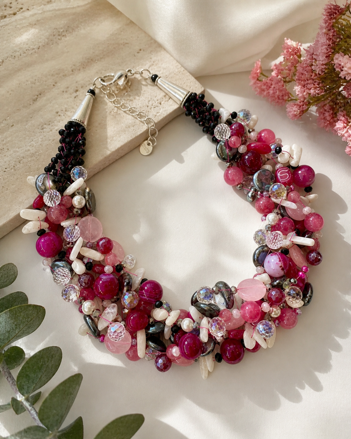 Collana artigianale rosa fucsia con pietre naturali e cristalli intrecciati, fotografia ambientata luminosa