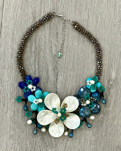 Collana artigianale estiva con fiore di madreperla centrale sui toni del turchese, dell’azzurro e del blu