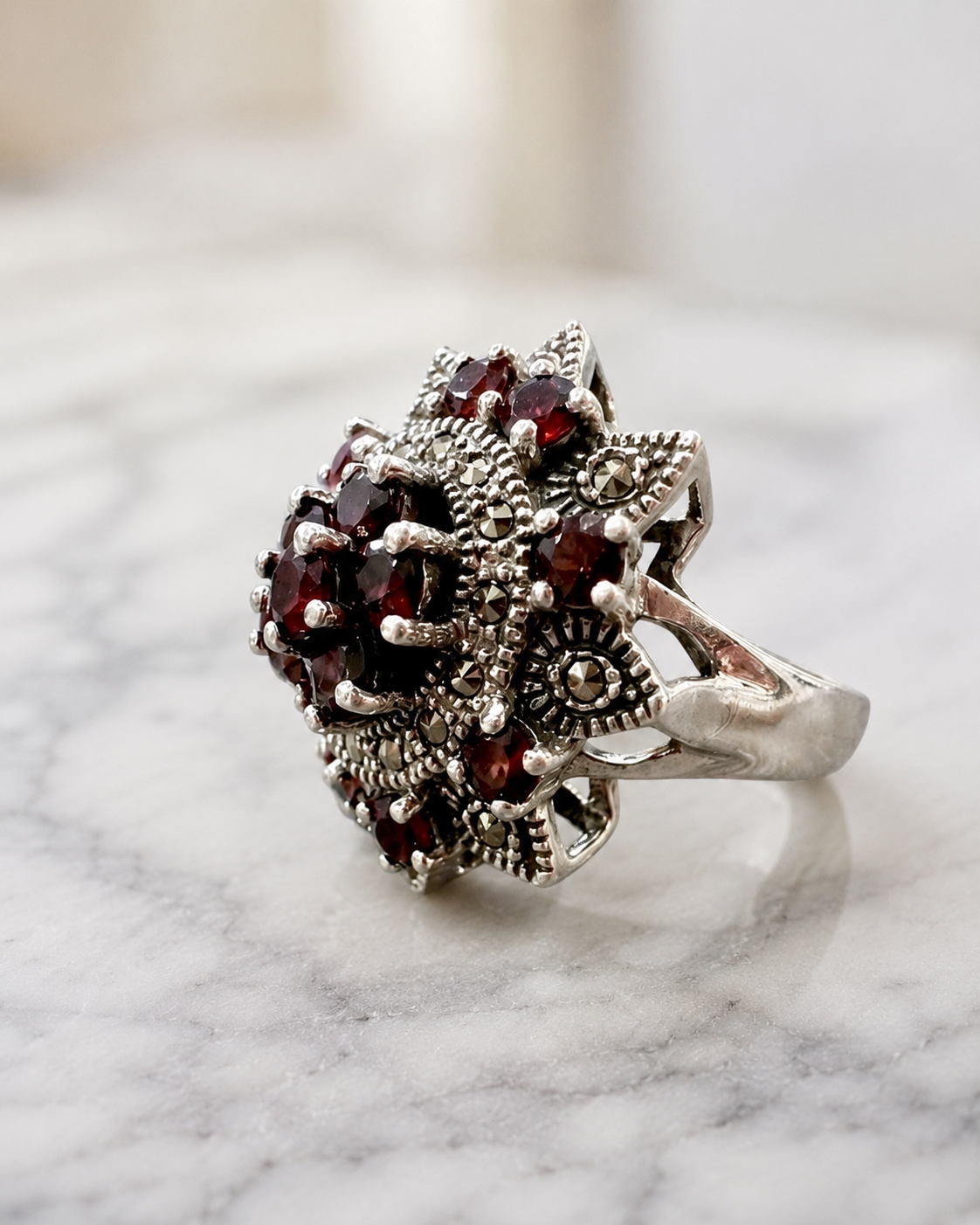 Anello in argento 925 con granati naturali e marcasiti, design floreale elegante.