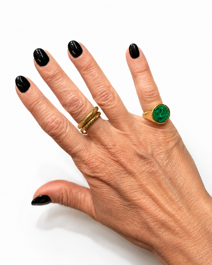 Anello chevalier in argento dorato con pietra verde effetto malachite indossato su mano femminile