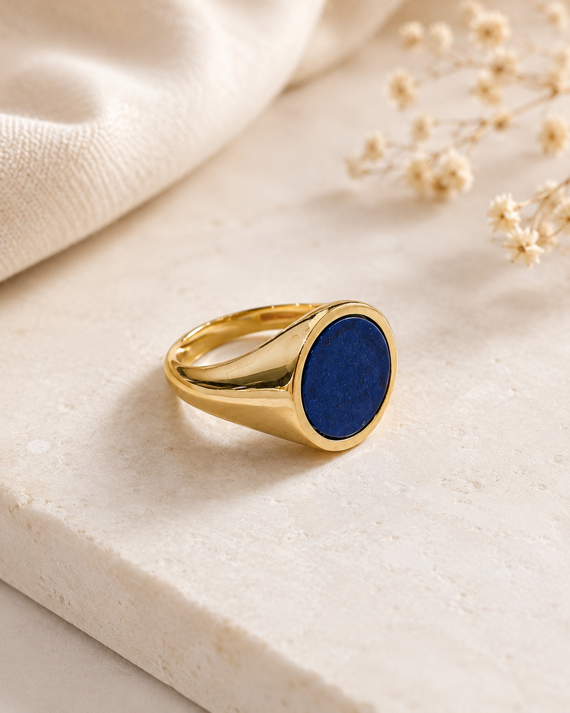 Dettaglio laterale anello chevalier in Argento 925 dorato con pietra blu lapis su sfondo neutro raffinato.