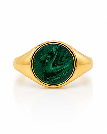 Anello chevalier in argento dorato con pietra verde effetto malachite indossato su mano femminile con manicure nera.