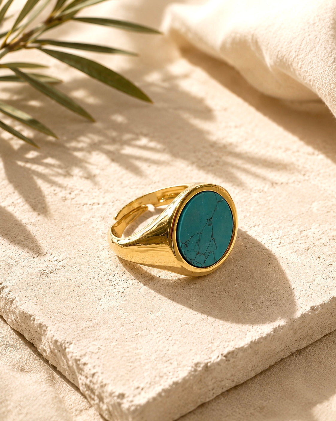 Anello chevalier in argento 925 dorato con pietra turchese effetto naturale su ambientazione neutra elegante.