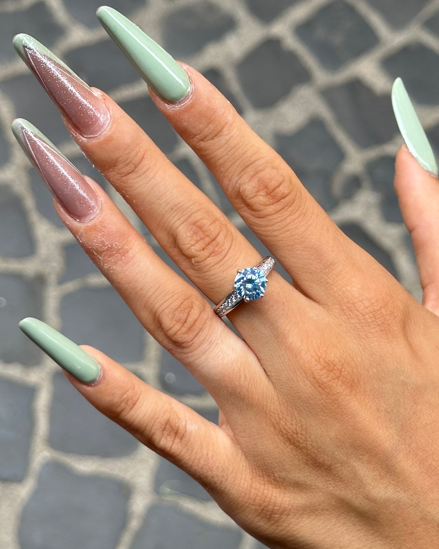 Anello solitario in Argento 925 con moissanite color acquamarina indossato sulla mano, dettaglio della pietra brillante e del pavé laterale.