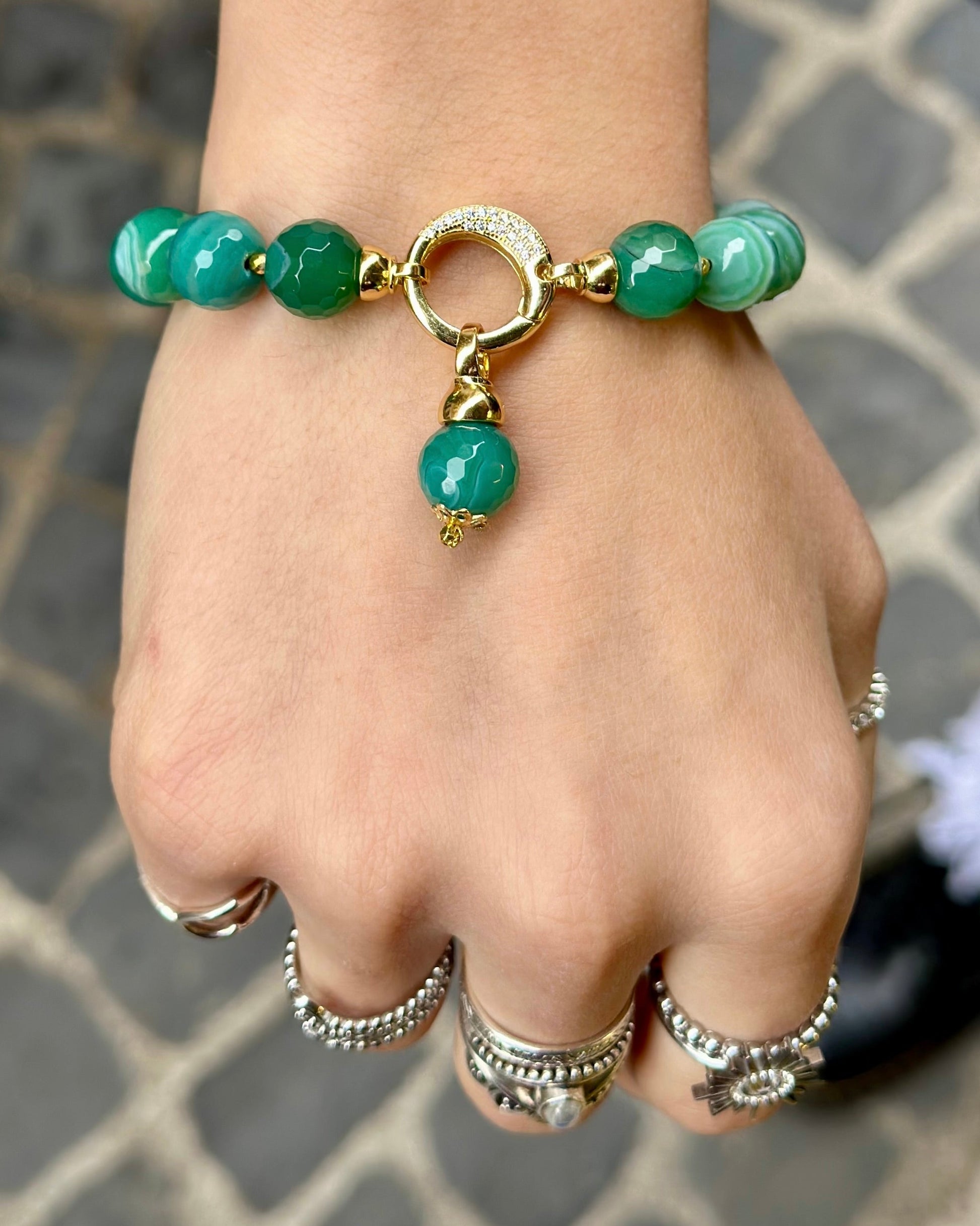     Modella che indossa un bracciale artigianale in Agata Brasiliana striata verde con dettagli in Argento 925 dorato, zirconi ed Ematite dorata.