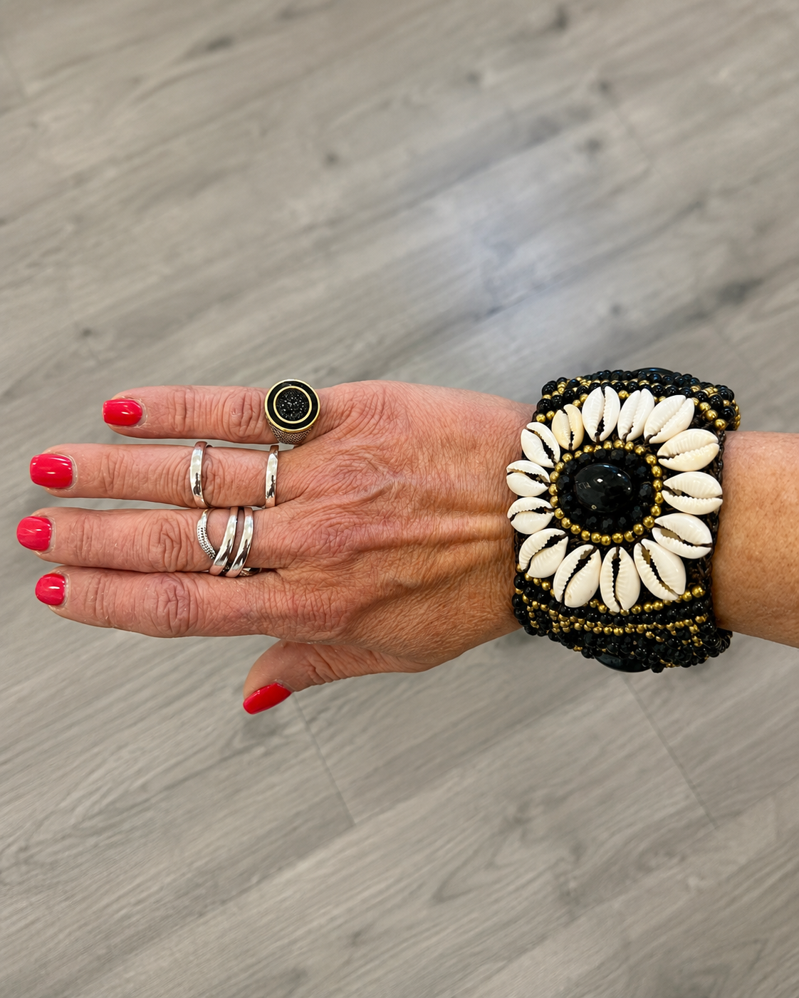 Bracciale boho con conchiglie naturali e pietra nera indossato al polso, stile etnico estivo.