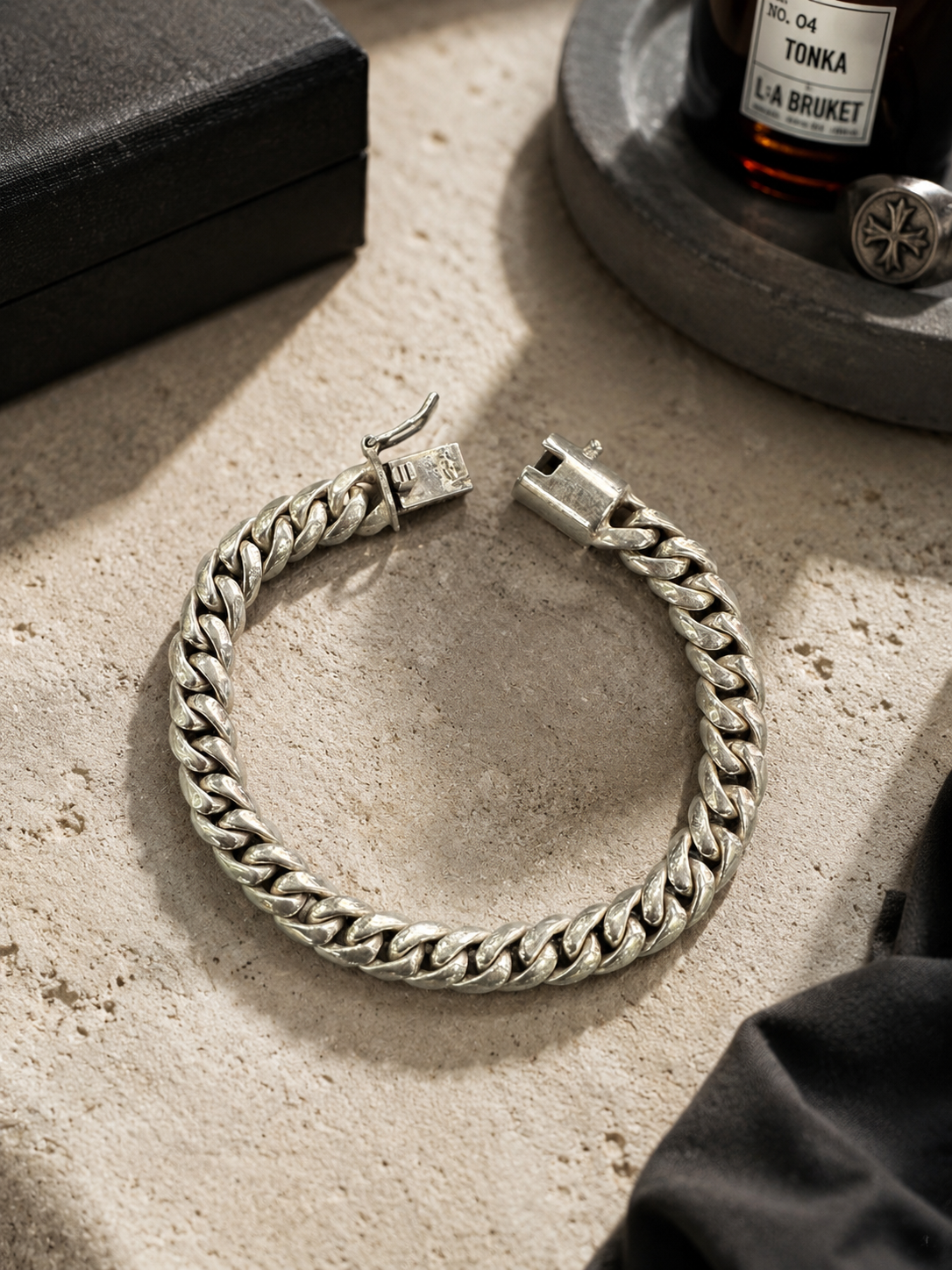 Bracciale Cuban Link in Argento 925 con finitura vintage ambientato su superficie scura effetto luxury, stile uomo elegante e contemporaneo.