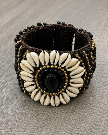 Bracciale etnico polsino con conchiglie naturali, pietra nera ovale e lavorazione artigianale in stile boho.