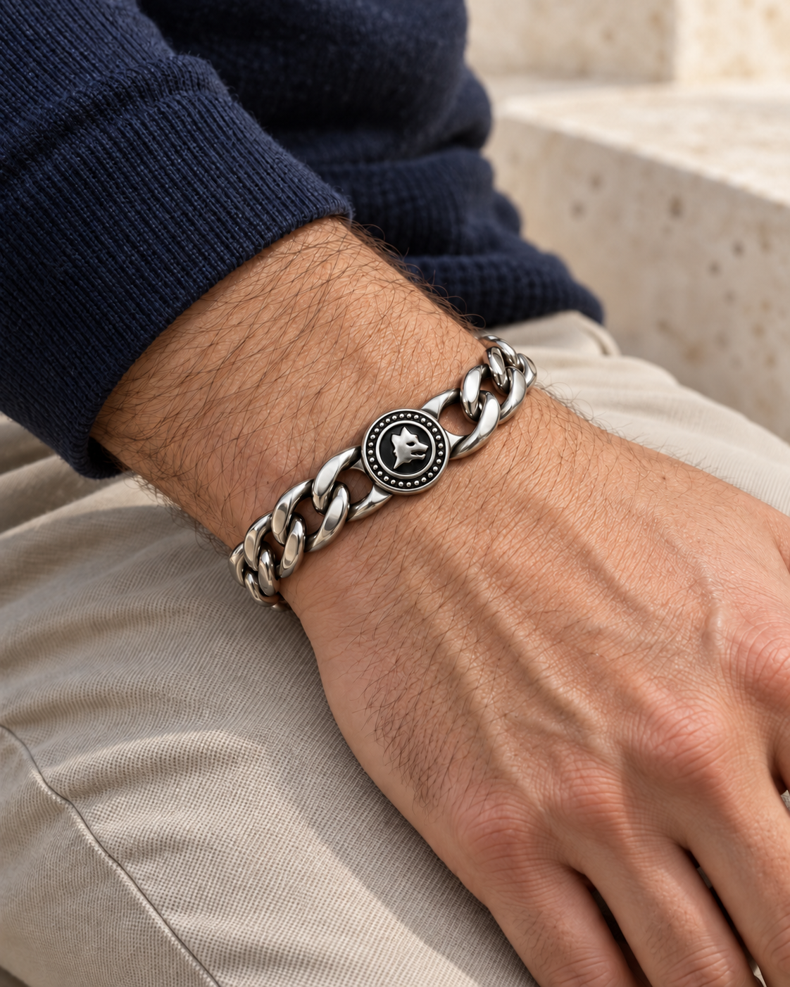 Bracciale Lupo in acciaio inox indossato al polso di un modello con maglia blu e pantaloni beige.
