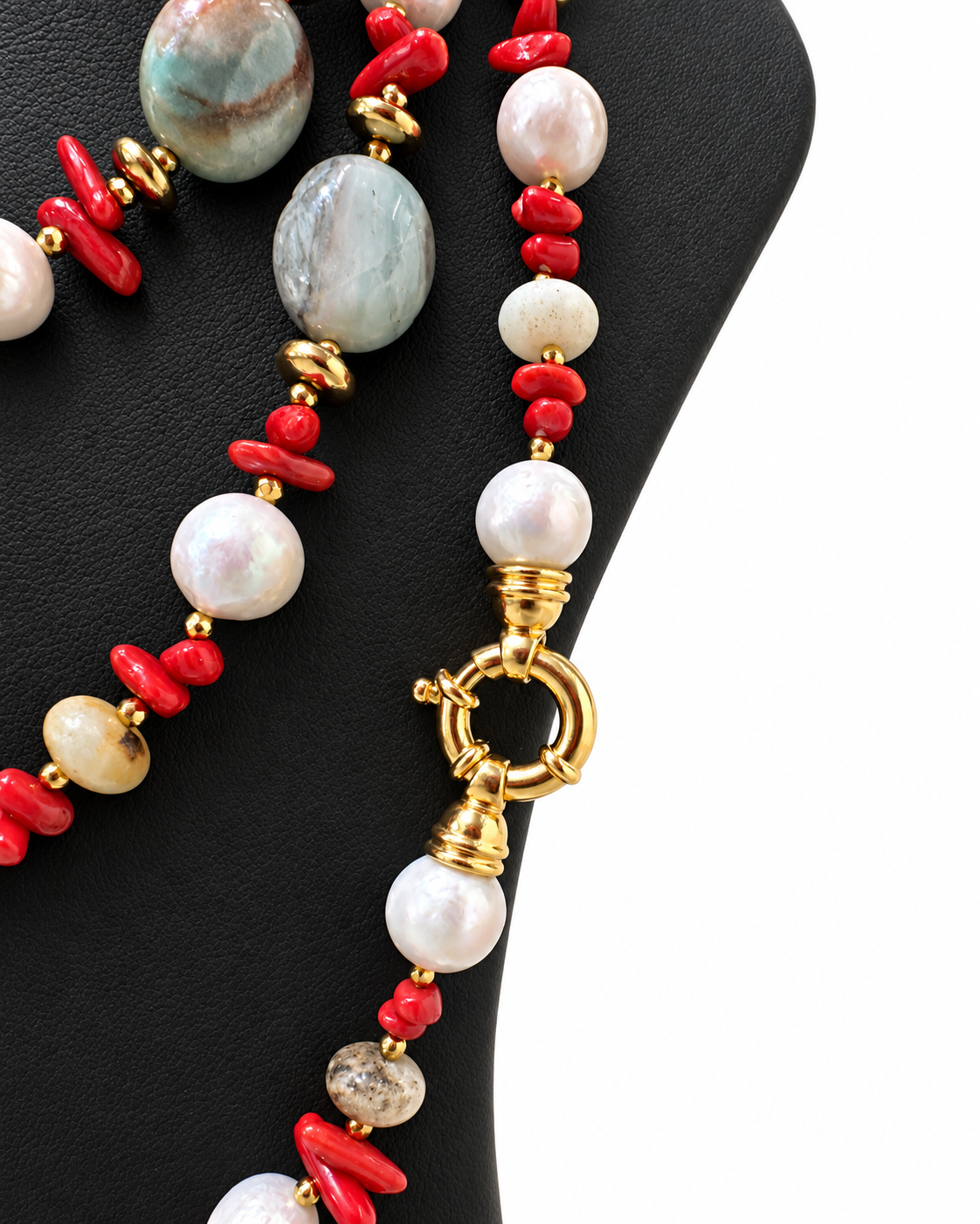 Chiusura ad anello in argento dorato con perla pendente, accanto ad amazzonite, corallo e perle naturali.