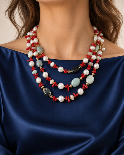 Collana in amazzonite, corallo e perle naturali indossata a tre giri su abito blu scuro.