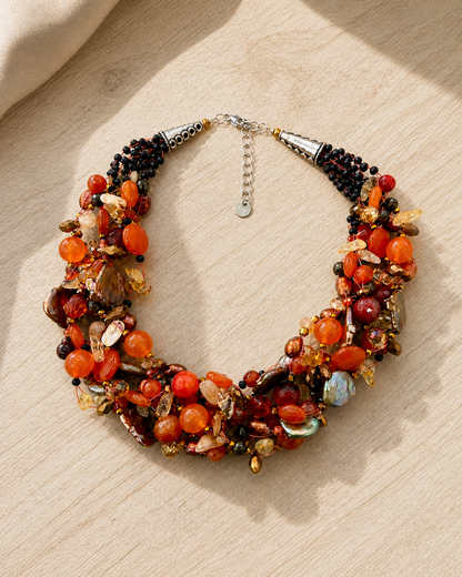 Collana artigianale arancio multifilo con pietre naturali e perle su fondo legno chiaro, stile elegante Attimi Gioielli