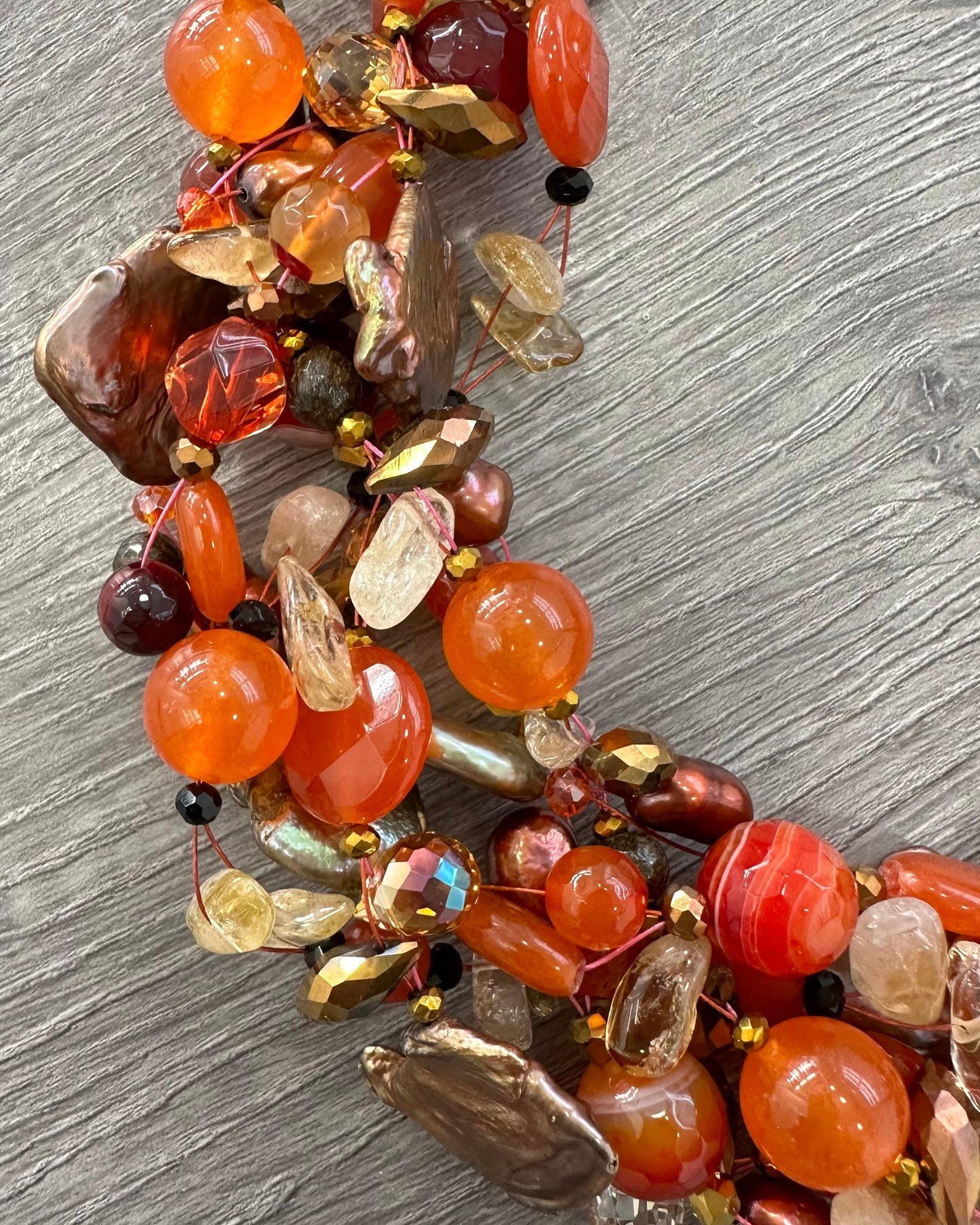 Dettaglio collana artigianale con pietre naturali arancio, perle e cristalli, lavorazione intrecciata Attimi Gioielli