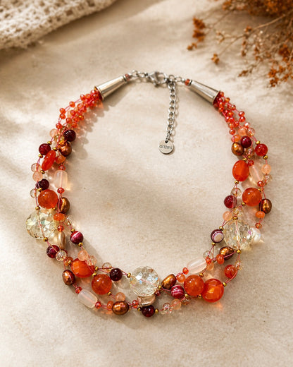 Collana artigianale intrecciata con pietre naturali arancio in ambientazione elegante, gioiello raffinato e luminoso