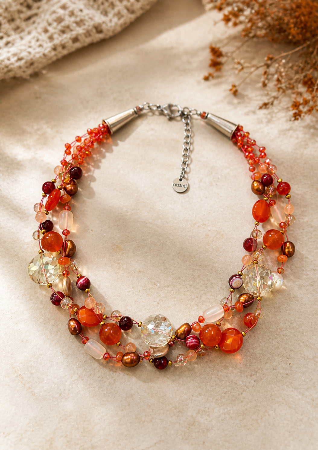 Collana artigianale intrecciata con pietre naturali arancio in ambientazione elegante, gioiello raffinato e luminoso