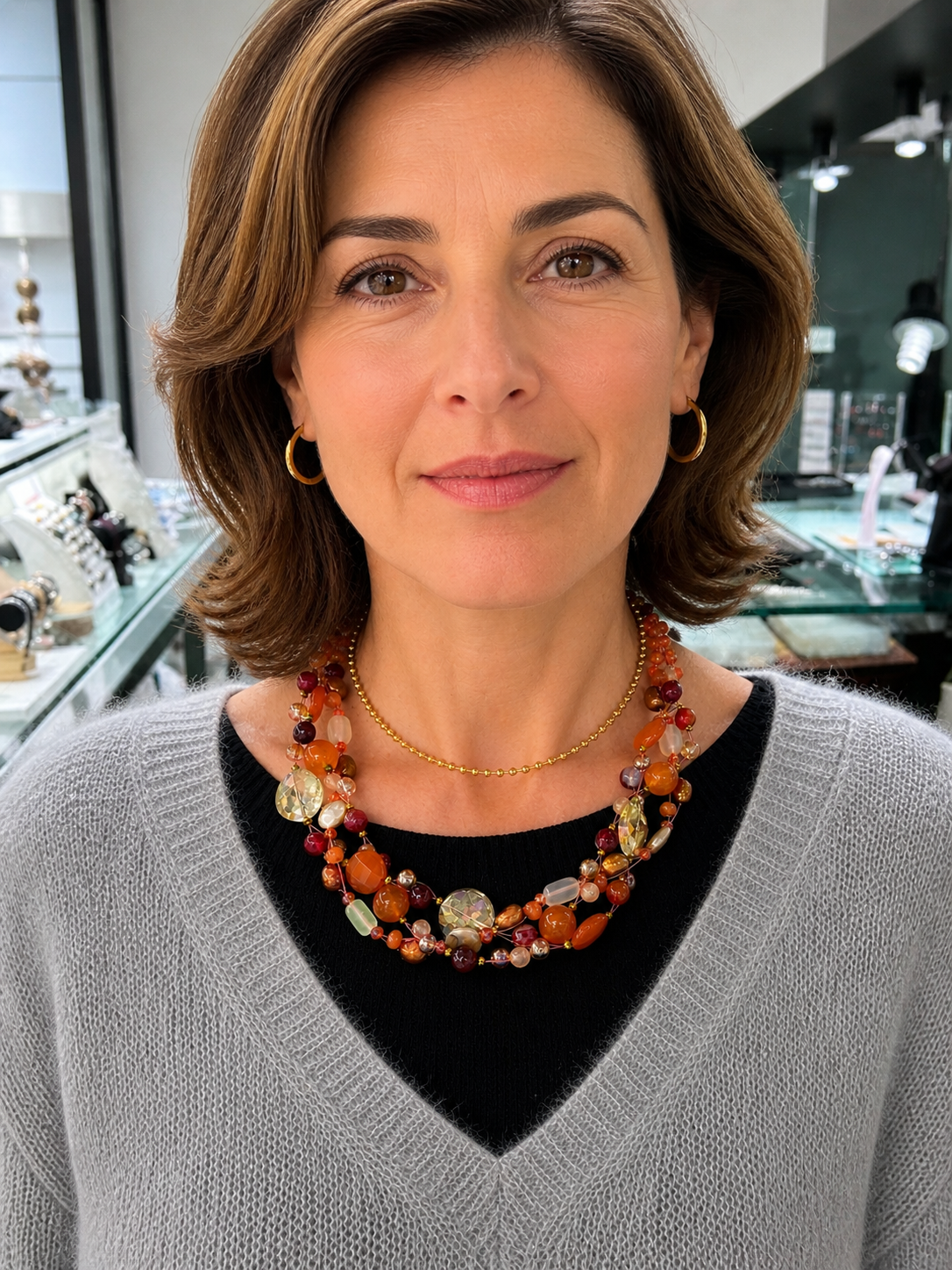 Collana artigianale intrecciata indossata su modella, gioiello con pietre naturali arancio, perle e cristalli, effetto elegante e luminoso