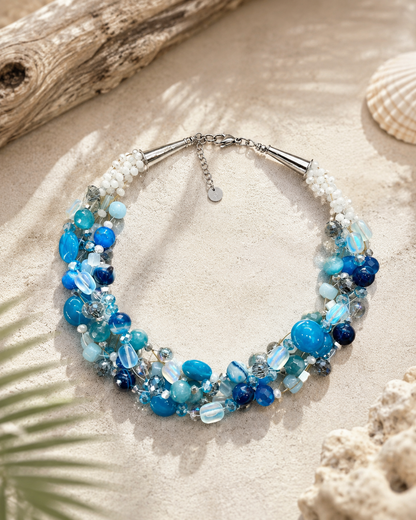     Dettaglio collana multifilo artigianale con cristalli luminosi, pietre naturali blu oceano e perline bianche intrecciate.