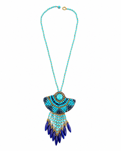 Collana boho turchese con maxi ciondolo ricamato e pendenti blu su fondo bianco.