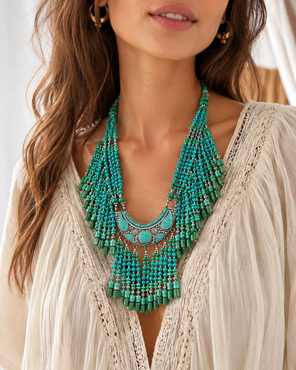 Modella boho con collana tibetana multistrato turchese e verde, centrale etnico in metallo argentato e dettagli artigianali pendenti.