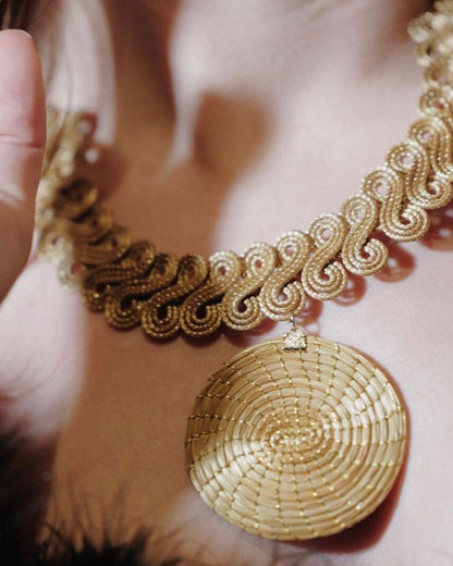 Dettaglio collana Capim Dourado con lavorazione intrecciata e ciondolo tondo, gioiello artigianale in oro vegetale Attimi Gioielli