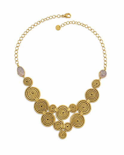Collana artigianale Capim Dourado con spirali intrecciate e pietra viola su sfondo bianco, stile boho elegante.