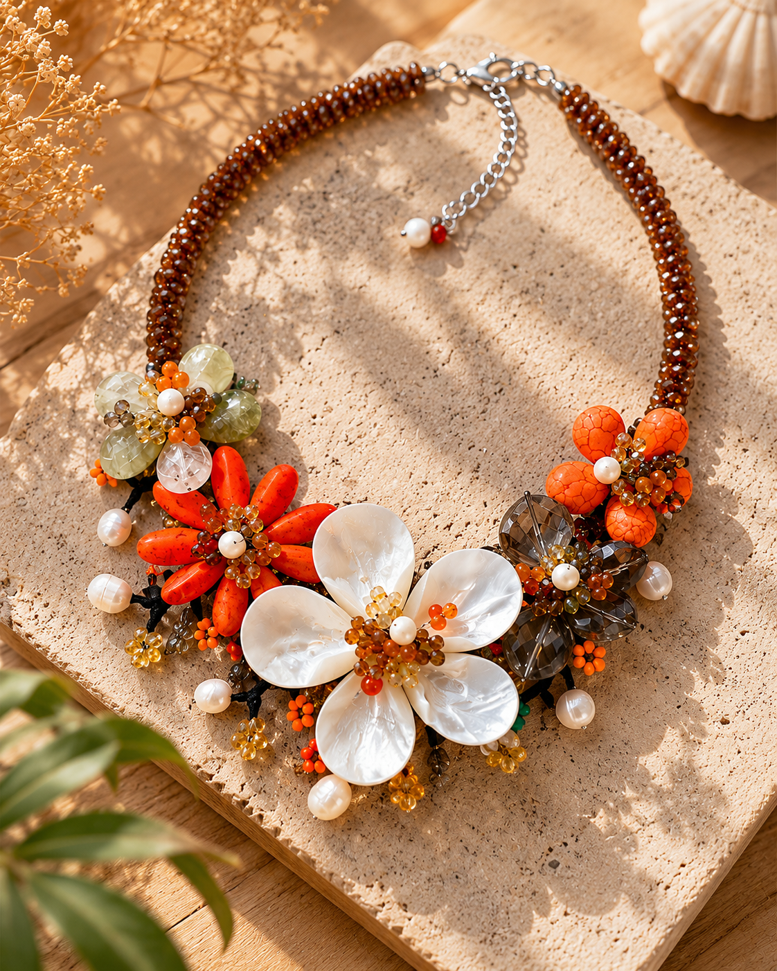 Collana floreale nei toni arancio, ambra e madreperla, fotografata in ambientazione naturale elegante e luminosa.