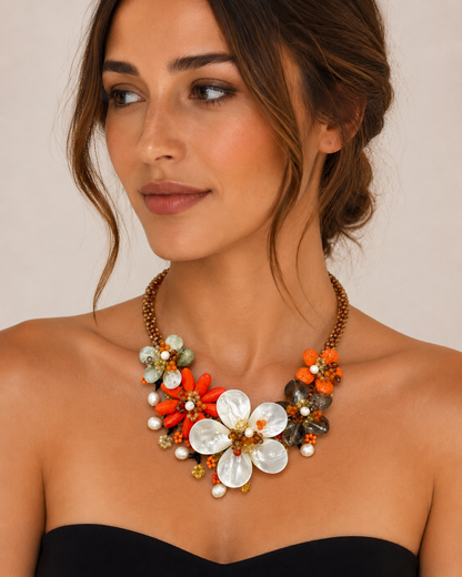 Modella con collana floreale artigianale nei toni arancio, madreperla, perle e cristalli, gioiello statement elegante e colorato.