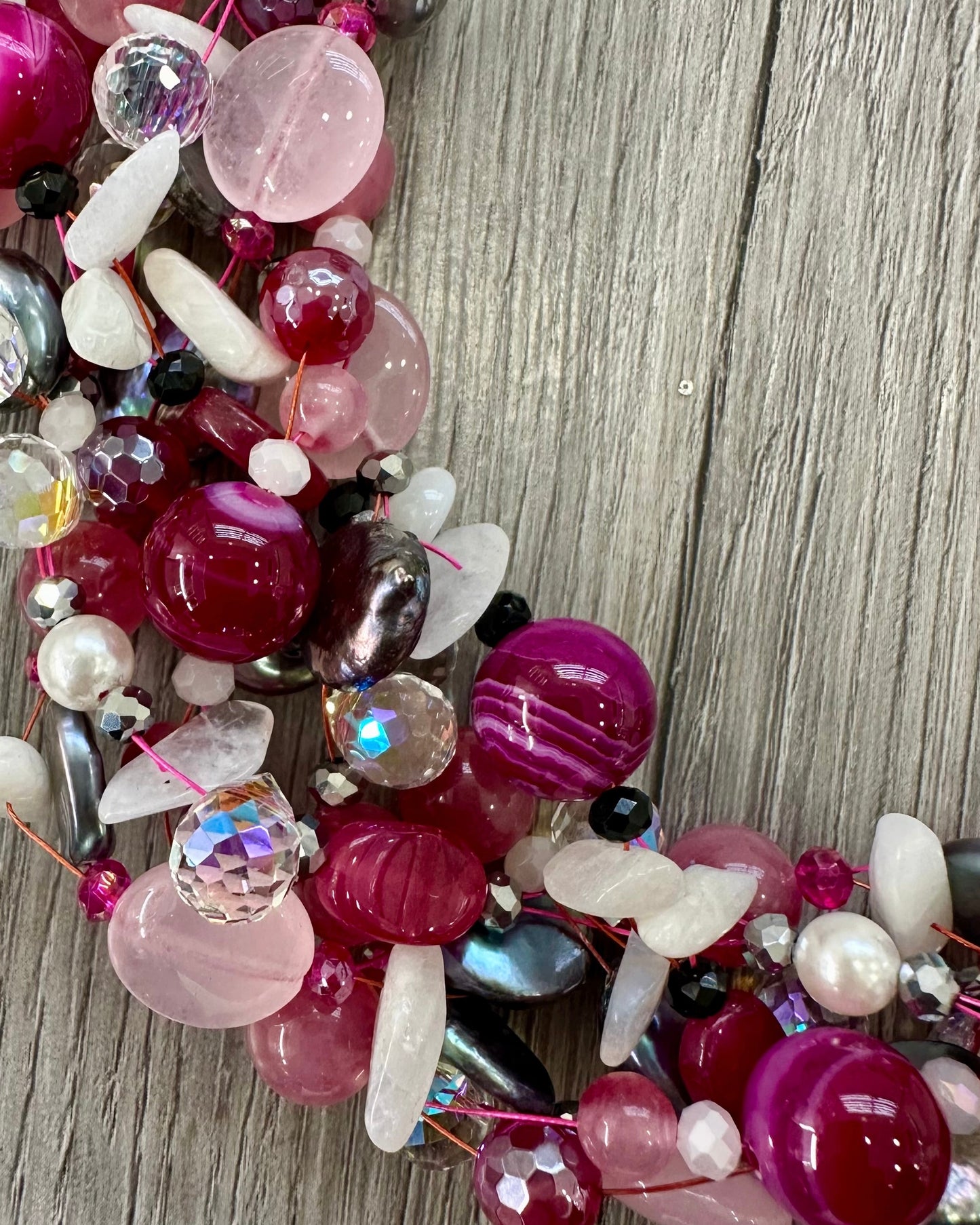Dettaglio collana intrecciata con perle, pietre rosa fuxia e cristalli luminosi