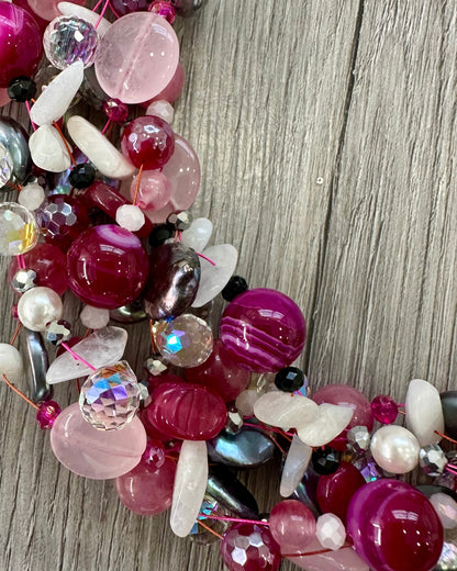 Dettaglio collana intrecciata con perle, pietre rosa fuxia e cristalli luminosi