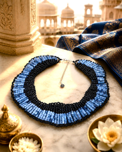 Collana ricamata con perline blu e nere e cristalli in un’ambientazione ispirata all’India.