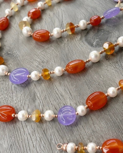     Dettaglio della collana artigianale con Giada viola, Giada arancio, Corniola, Perle ed Ematite rosata, con particolare delle pietre naturali e della lavorazione.