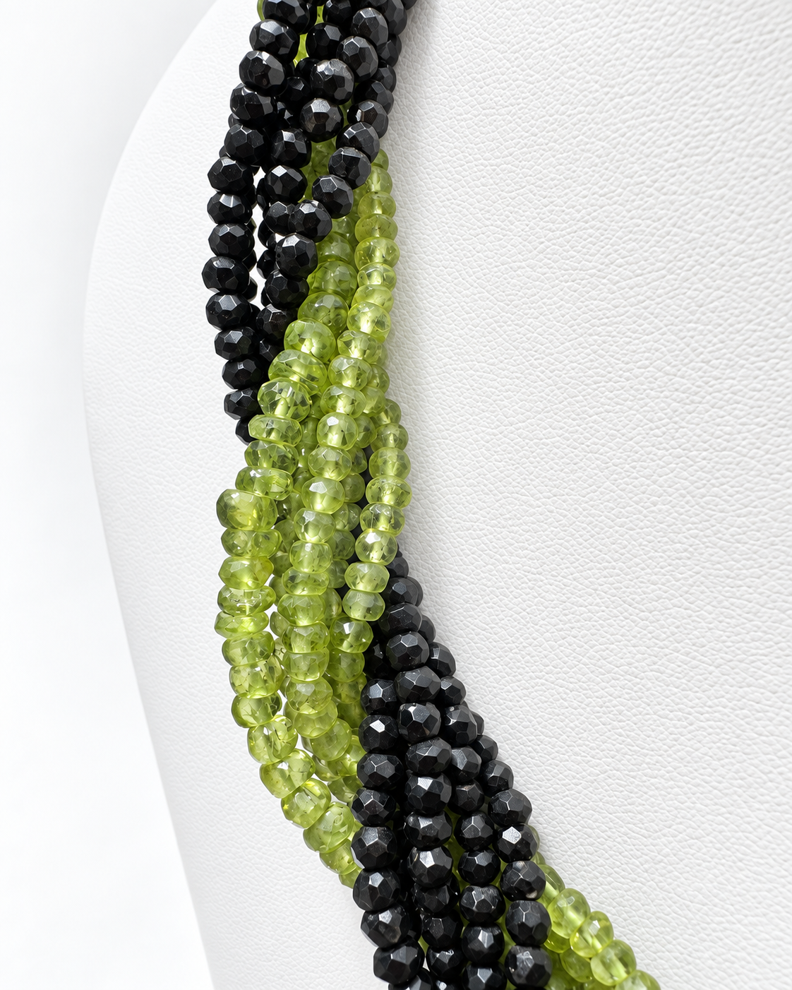 Dettaglio delle pietre di peridoto e onice nero, con forme e dimensioni diverse, sul busto bianco