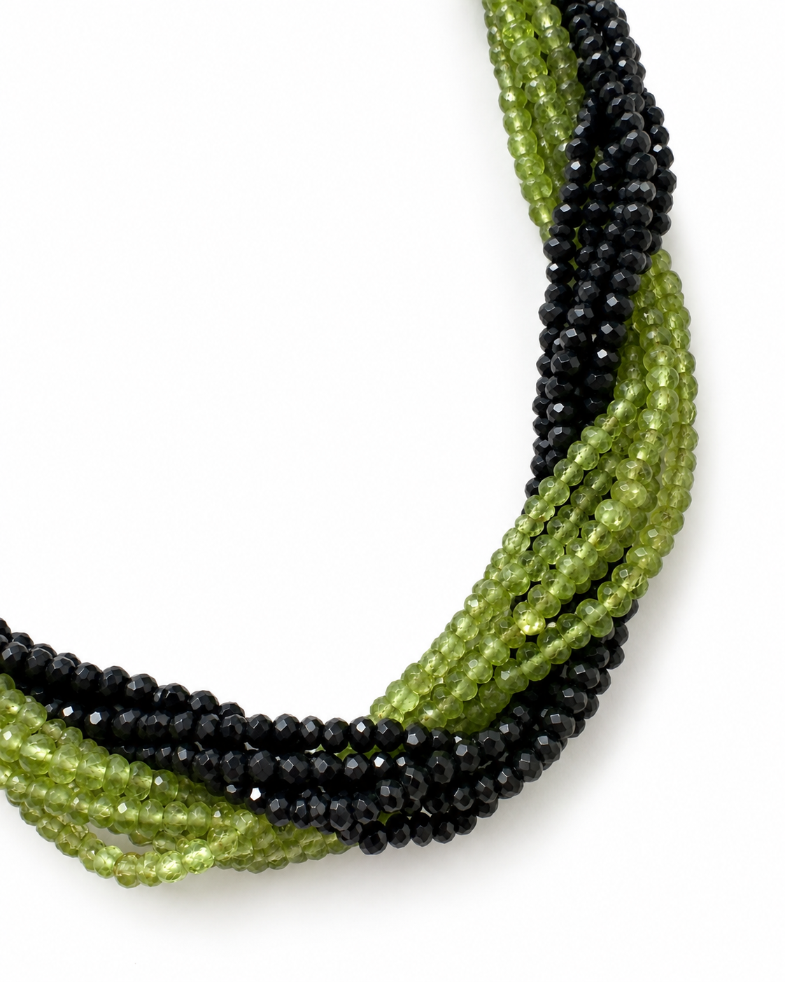 Dettaglio ravvicinato dei fili di peridoto verde e onice nero sfaccettati su fondo bianco