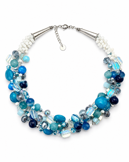     Collana artigianale multifilo con pietre naturali blu e azzurre, cristalli sfaccettati e dettagli in acciaio inox su sfondo bianco.