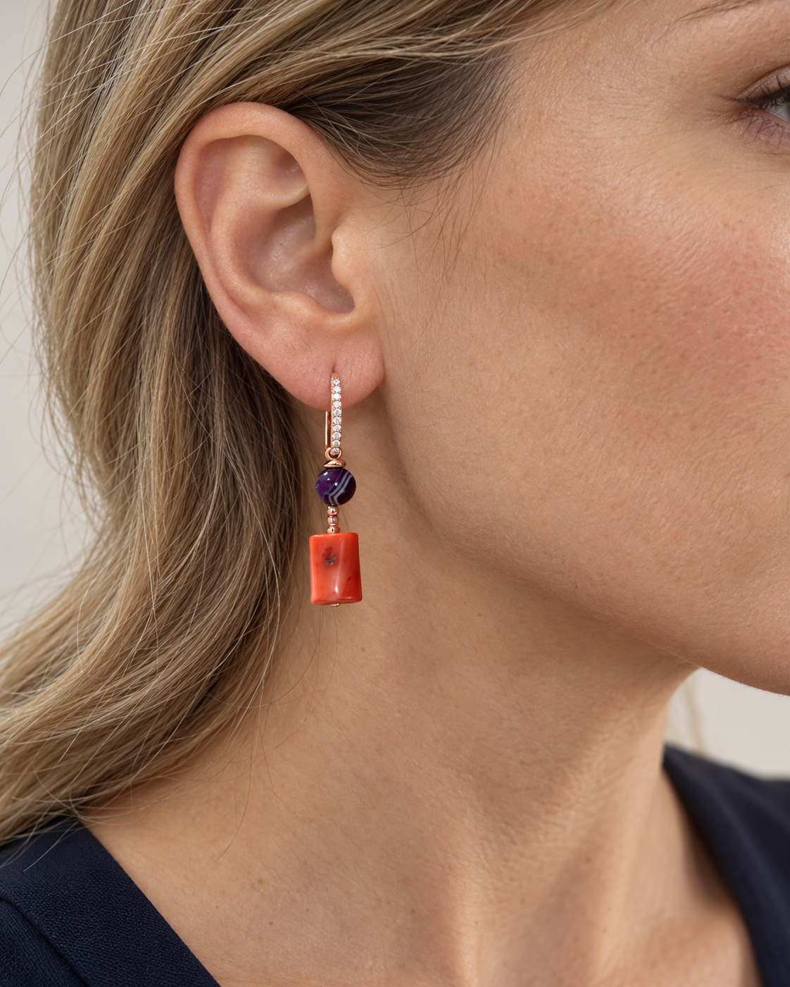 Orecchino pendente in Argento 925 rosato con Corallo bambù arancio e Agata brasiliana viola, indossato da una modella di profilo.
