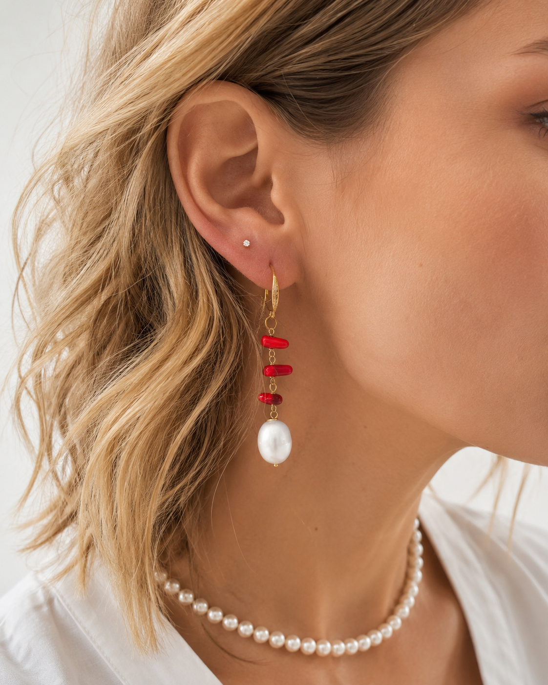 Modella che indossa orecchini in Argento 925 dorato con corallo rosso naturale e perla naturale.