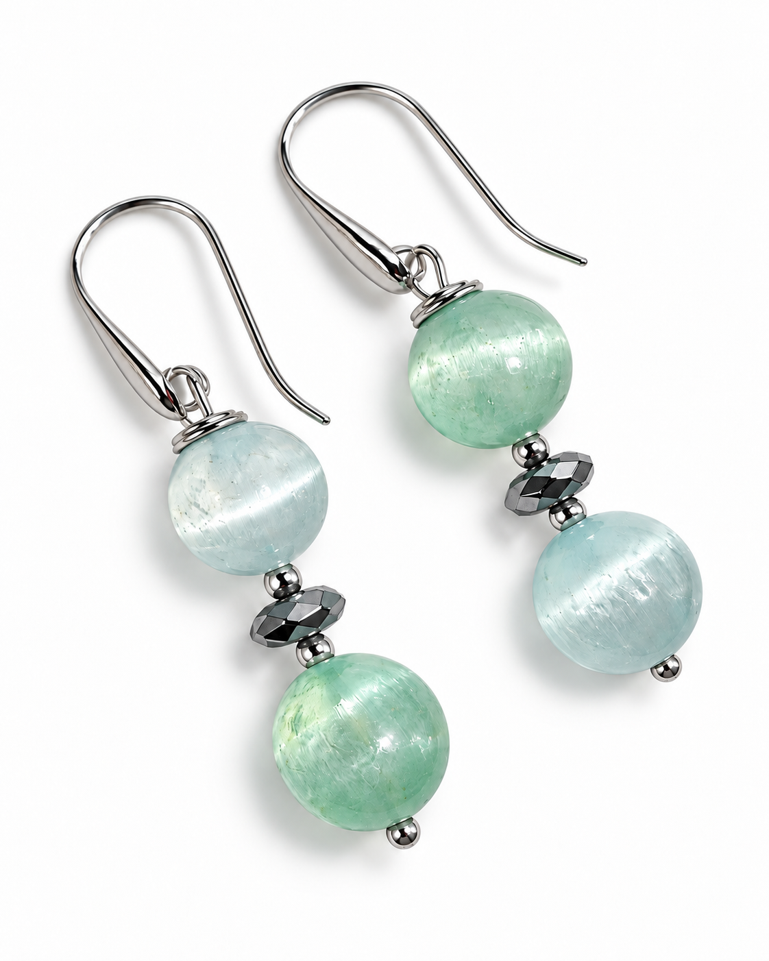 Orecchini pendenti in Argento 925 con sfere di Selenite verde acqua e azzurro chiaro, appoggiati su fondo bianco.