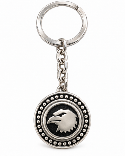 Portachiavi in acciaio inox con medaglione rotondo, aquila color argento su fondo nero, catena a maglie e anello, su sfondo bianco.