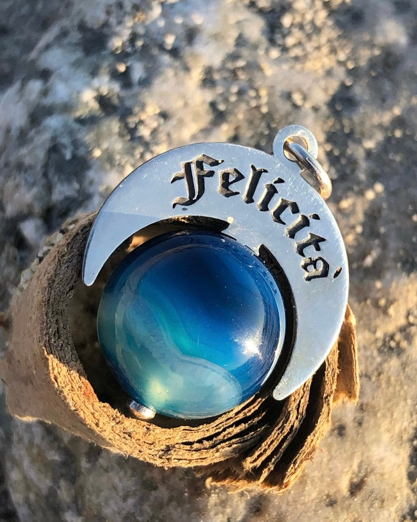 Talismano Felicità artigianale in Argento 925 con Agata Brasiliana Blu Striata fotografato su legno.