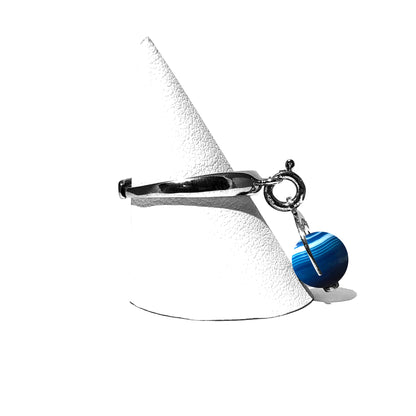 Caratteristiche: L'anello è composto da una base in Argento 925 e un Charm Naja. Quest'ultimo è inciso e smaltato, con scritte in carattere gotico e una Pietra Dura. Il Charm è attaccato alla base dell'anello con un piccolo moschettone che permette l'eventuale riposizionamento del charm stesso su un bracciale , una collana o un qualsiasi altro supporto.