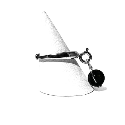 Caratteristiche: L'anello è composto da una base in Argento 925 e un Charm Naja. Quest'ultimo è inciso e smaltato, con scritte in carattere gotico e una Pietra Dura. Il Charm è attaccato alla base dell'anello con un piccolo moschettone che permette l'eventuale riposizionamento del charm stesso su un bracciale , una collana o un qualsiasi altro supporto